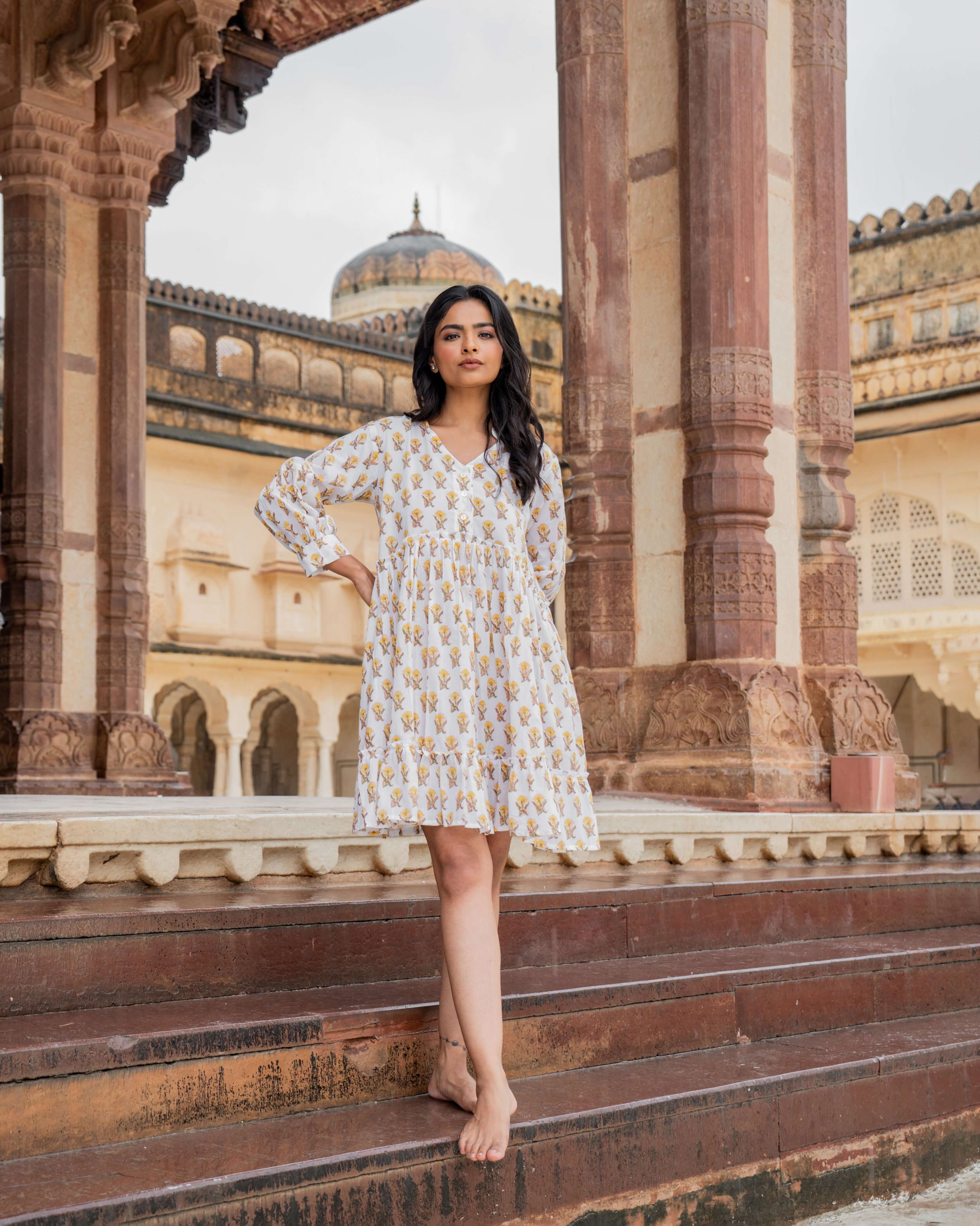 Timeless white cotton midi dress featuring a vibrant sunflower print, long sleeves, and a flowy fit, offering comfort and style for every occasion.