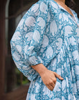 Chic blue cotton midi dress adorned with beautiful floral patterns, featuring a front tie cord, side pockets, and a comfortable, flowy design.