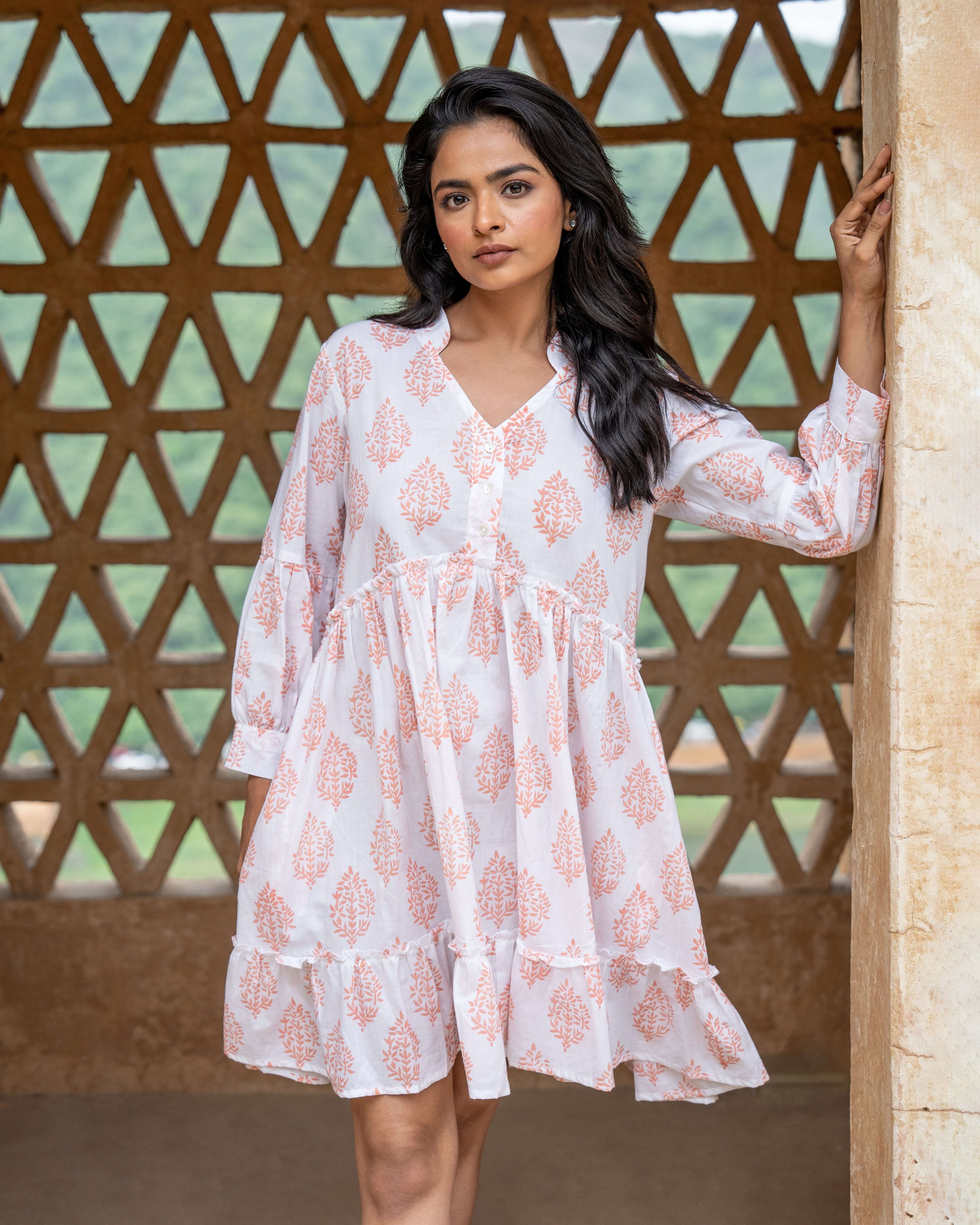 Stylish white midi dress adorned with terracotta blooms, featuring a relaxed fit, long sleeves, and side pockets for a perfect blend of comfort and style.