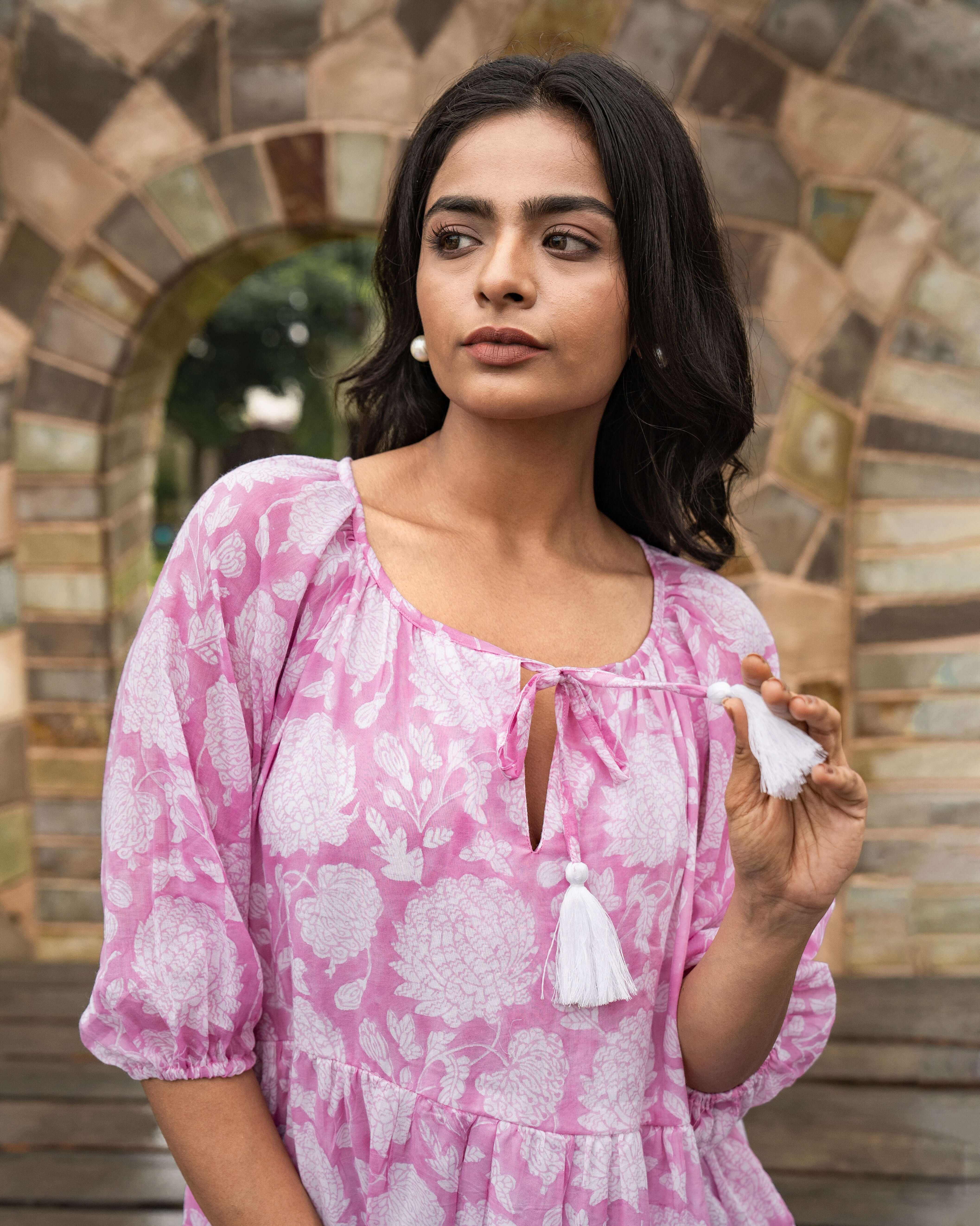 Elegant pink cotton midi dress adorned with floral patterns, featuring relaxed sleeves and side pockets, perfect for any occasion with effortless style.