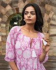 Elegant pink cotton midi dress adorned with floral patterns, featuring relaxed sleeves and side pockets, perfect for any occasion with effortless style.