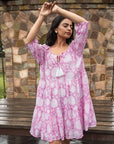 Charming pink cotton midi dress with floral designs, showcasing a flowy silhouette, relaxed sleeves, and a front tie cord for a chic touch.