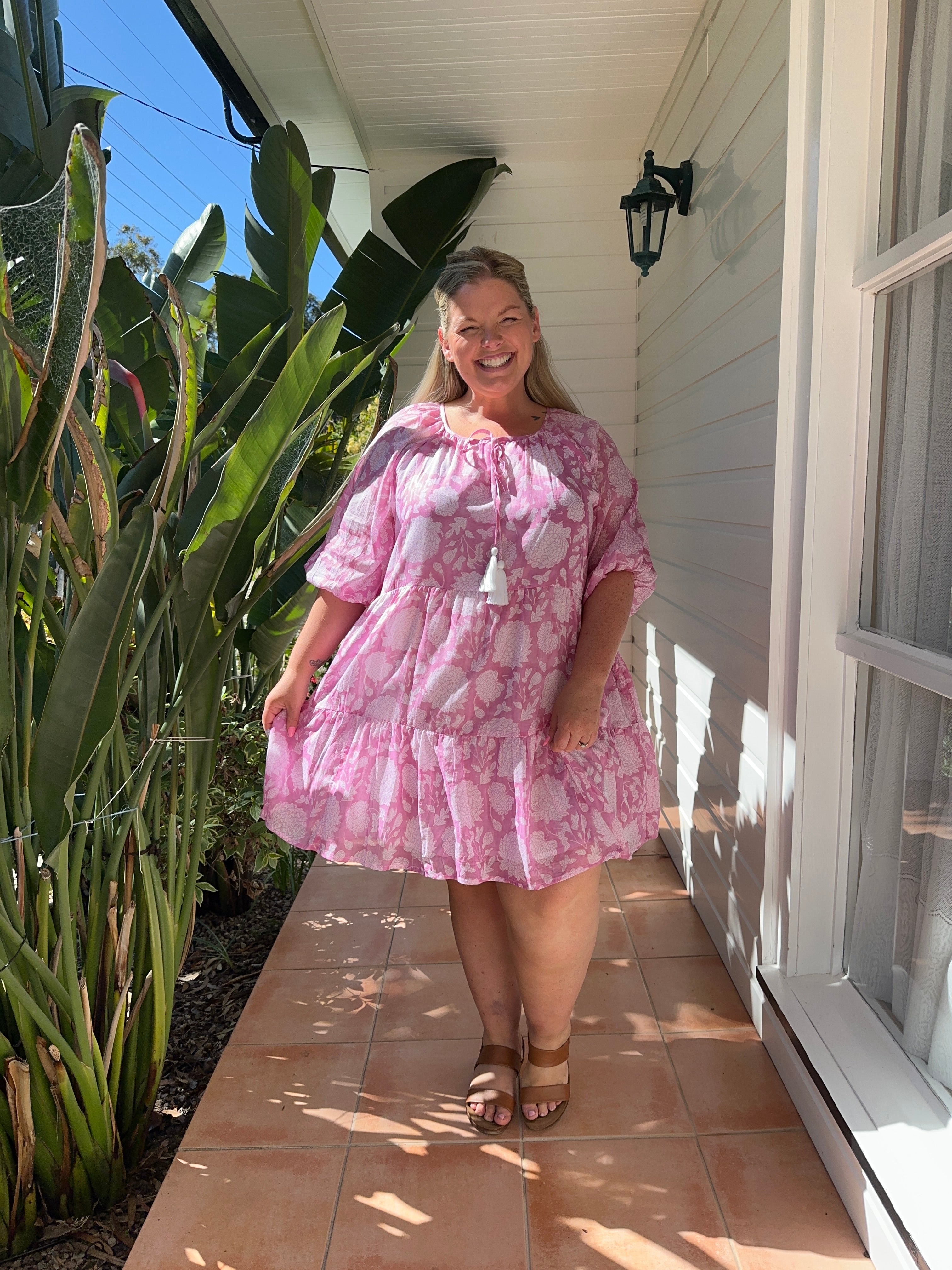 Playful pink floral midi dress with a fitted waist and flowing skirt, perfect for garden parties or summer events.