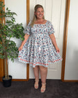 Blue midi dress featuring a fitted shirred bodice and a flowing, mid-length skirt.