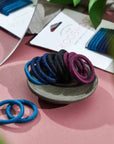 "Discover Kooshoo's plastic-free mini hair ties. Stylish, sustainable, and available in purple, black, and blue. Great for you and the planet!"