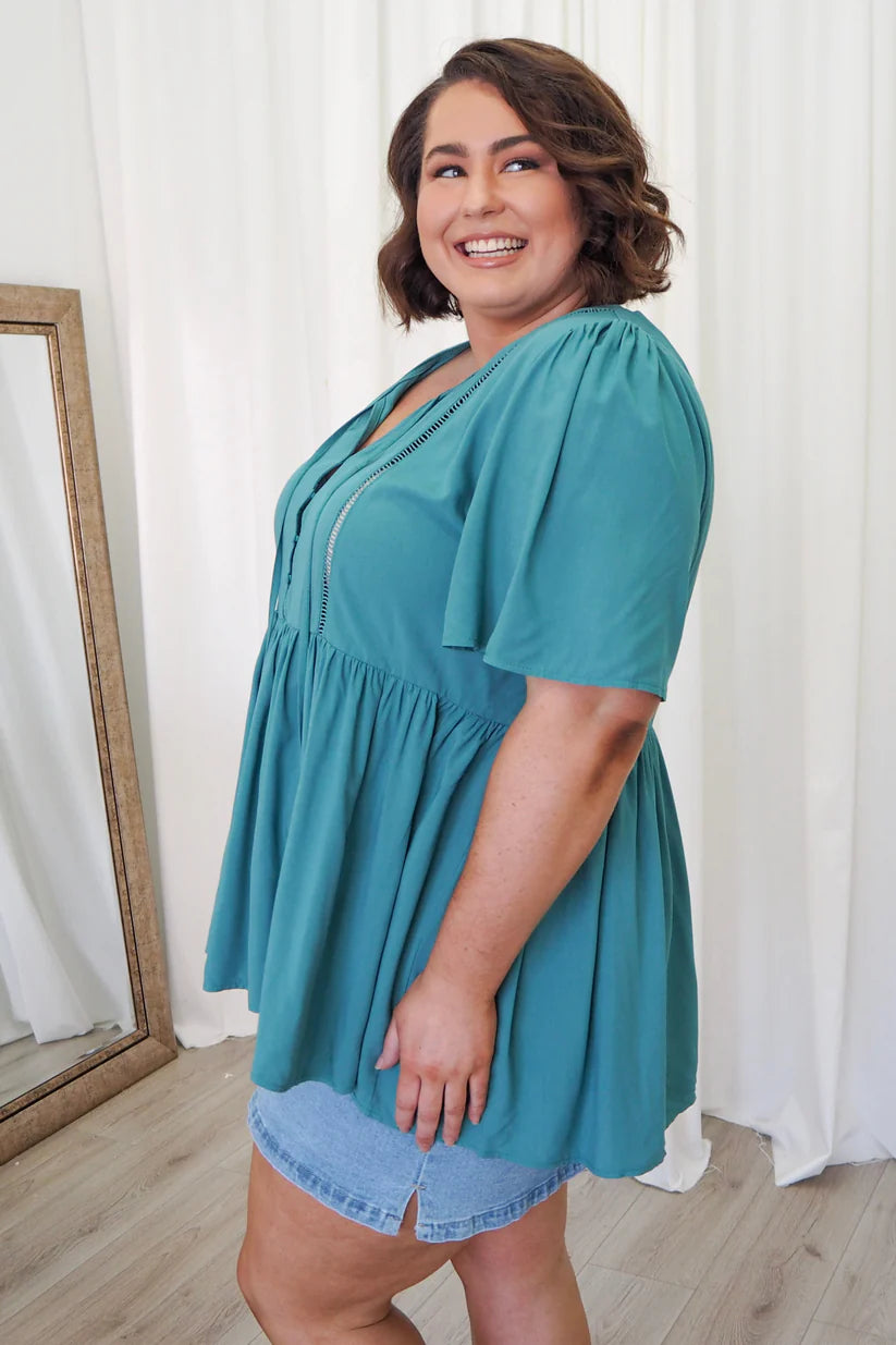 Curves in teal! Discover our irresistible plus-size babydoll top. Perfect fit, stunning style. Elevate your look today!